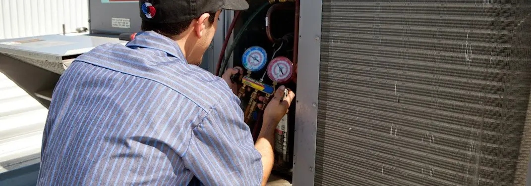 HVAC technician servicing a condenser unit in Bellair-Meadowbrook Terrace